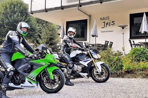Zwei Motorradfahrer in Lederkombi vor dem Iris Valley Lodge des Iris Valley Lodge in Herzberg am Harz, motorradfreundliches Hotel im Harz mit sicheren Stellplätzen