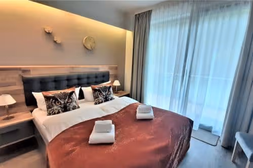 Komfortables Hotelzimmer im Iris Valley Lodge in Herzberg am Harz mit Doppelbett warmen Tönen und Tür zum Balkon, Boutiquehotel mitten in der Natur